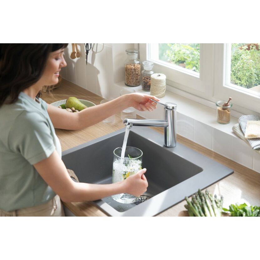 Person füllt Glas mit Wasser an HG Zesis M33 SPTM Küchenarmatur