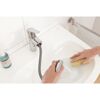 Person reinigt Waschbecken mit Schwamm und Schlauchbrause.