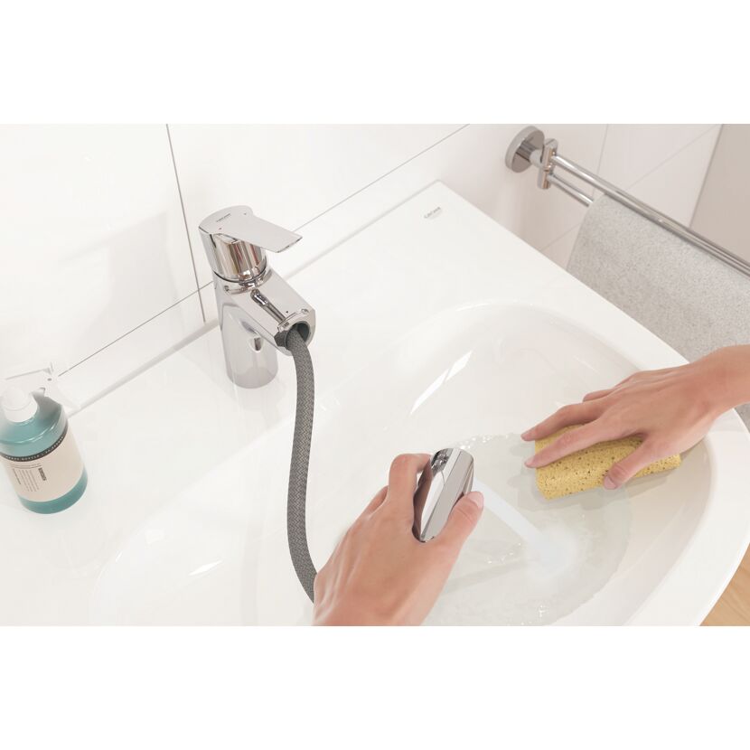 Person reinigt Waschbecken mit Schwamm und Schlauchbrause.