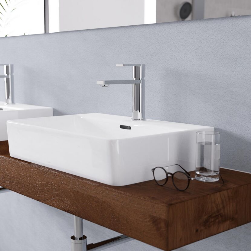 Waschbecken mit Armatur und Glas Wasser auf Holzplatte