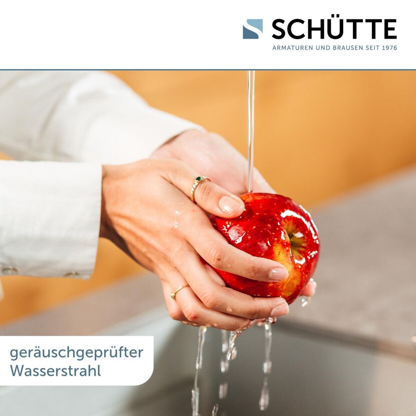 Person hält Apfel unter Wasserhahn