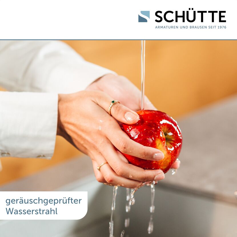 Person hält Apfel unter Wasserstrahl