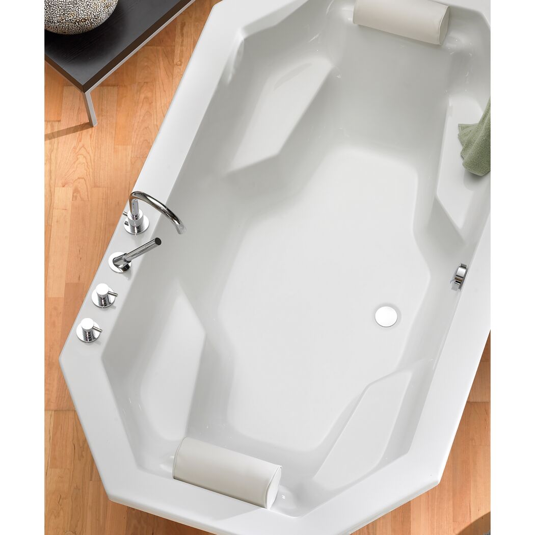 Weiße, achteckige Badewanne mit Handtuch und zwei Nackenkissen.