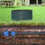Schwarzes HDPE-Rohr mit blauer Linie auf Rasen und unter der Erde mit blauer Verbindung