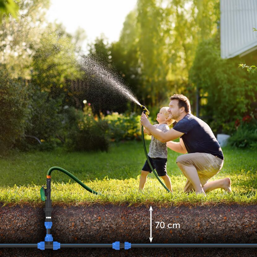 Vater und Kind spielen mit Gartenschlauch und unterirdischer HDPE-Rohrleitung