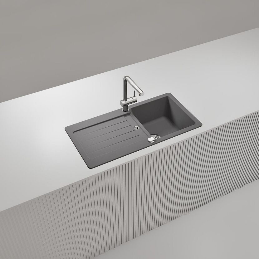 Graue Spüle mit Abtropffläche und Wasserhahn.