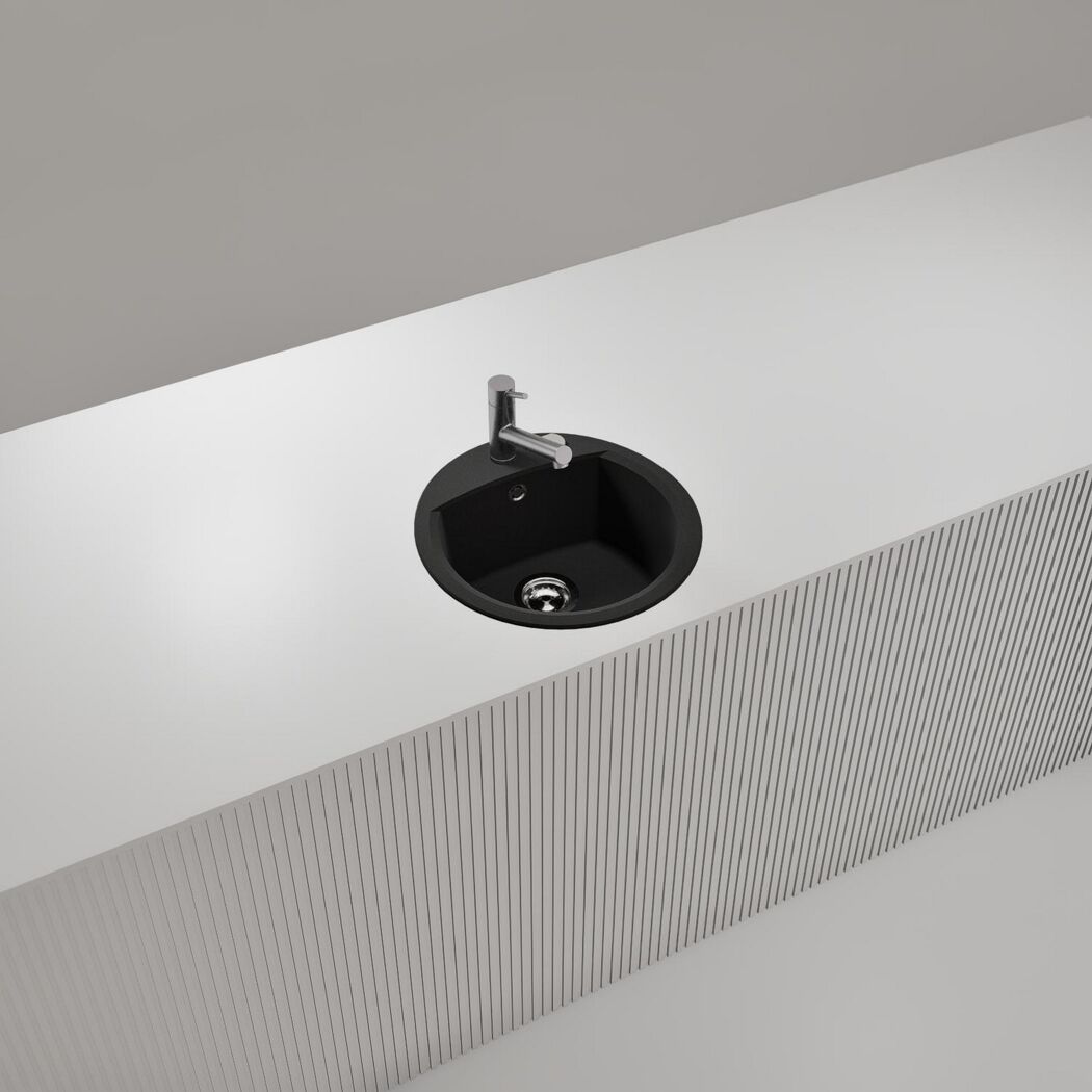 Schwarzes rundes Spülbecken in weißer Arbeitsplatte.