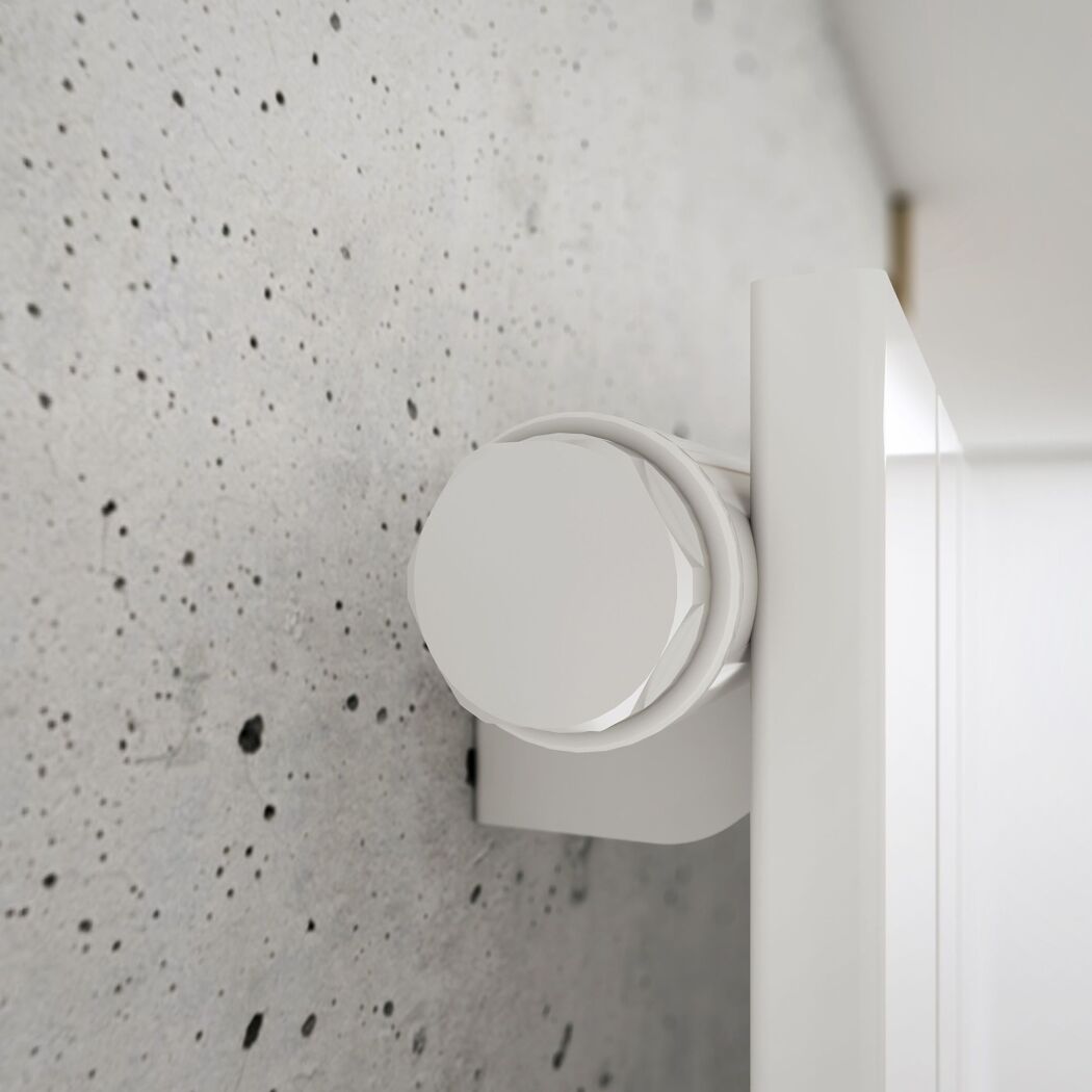 Weißer Heizkörper mit Thermostat an Betonwand