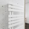 Weißer Handtuchheizkörper an grauer Betonwand.