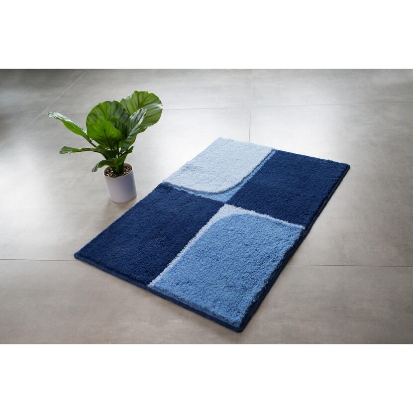 Blauer Badteppich auf grauem Fliesenboden.