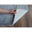 Hand hebt grauen Teppich an