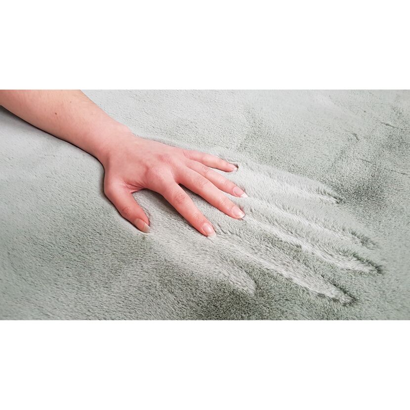 Hand streichelt einen mintgrünen Teppich