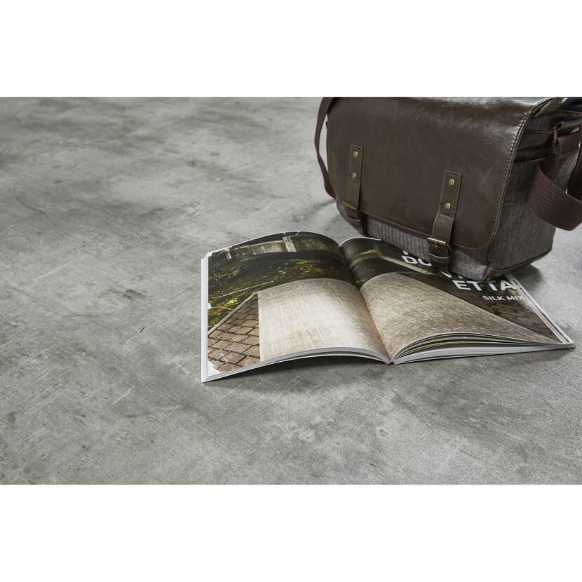 Braune Ledertasche und Zeitschrift auf Betonboden