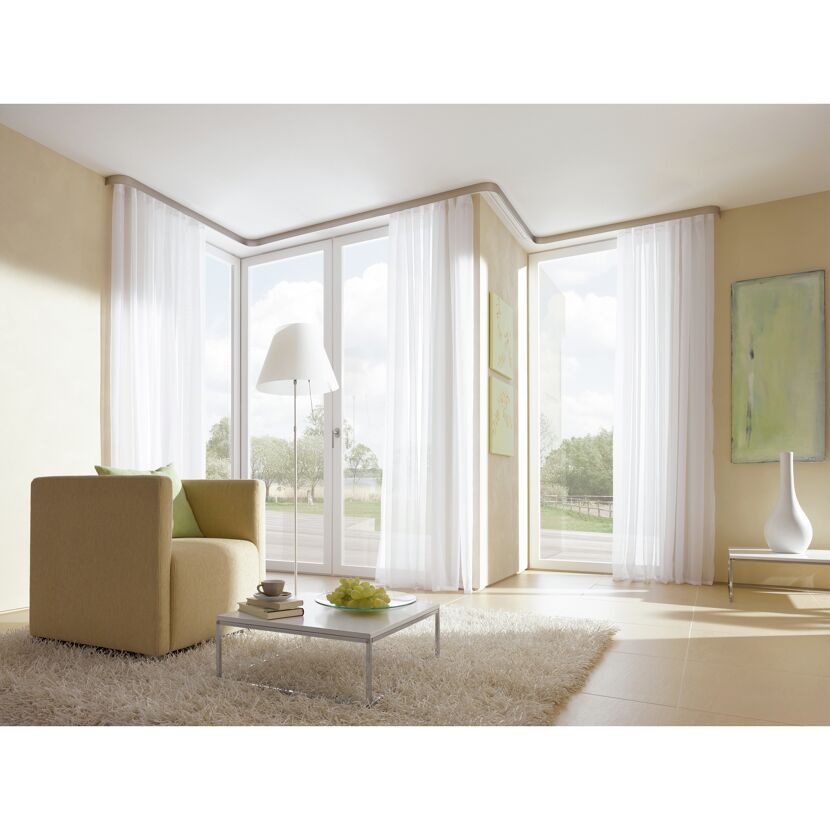 Wohnzimmer mit Blick in den Garten. Die Fenster sind mit weissen Vorhängen dekoriert.