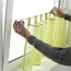 Person bringt Klemmvitrage an Fenster an