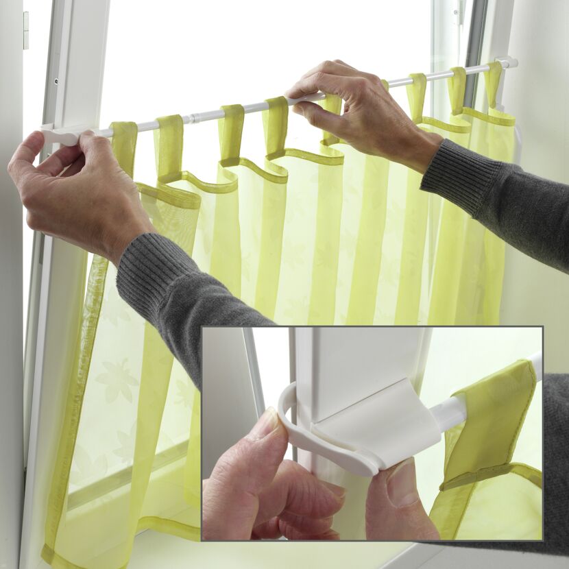 Person befestigt Klemmvitrage am Fenster.