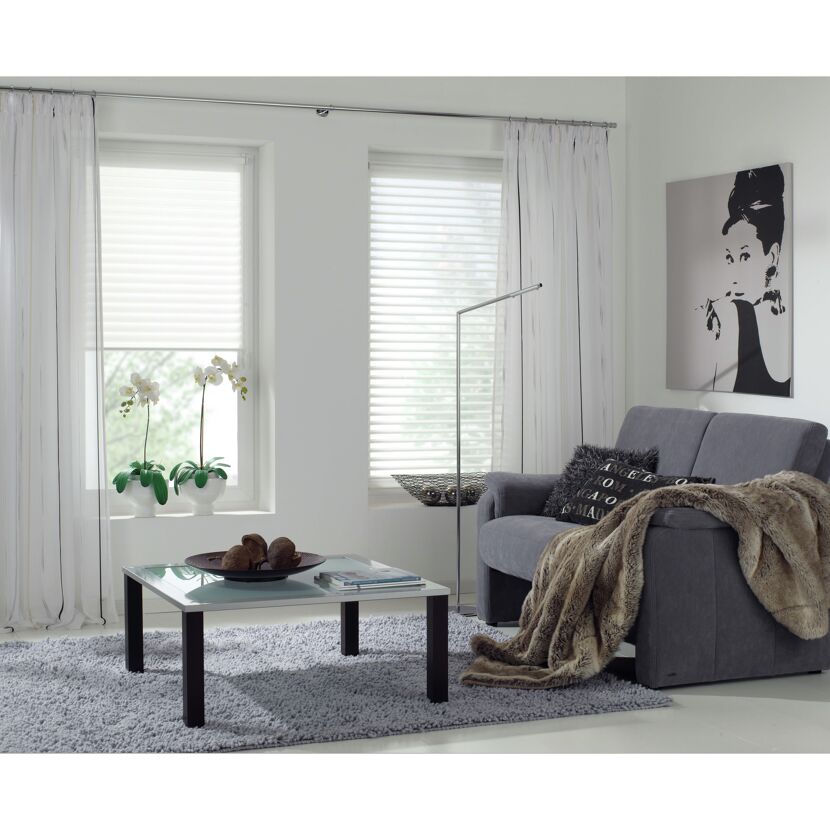 Wohnzimmer mit Vorhängen, Faltrollos, Sofa und Couchtisch.