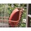 Geflochtener Gartenstuhl mit orangenem Kissen
