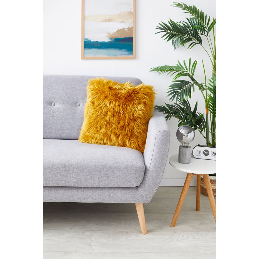 Senfgelbes Kissen auf grauem Sofa