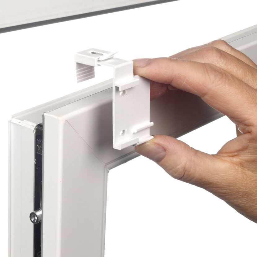 Person befestigt einen Halter am Fensterrahmen.