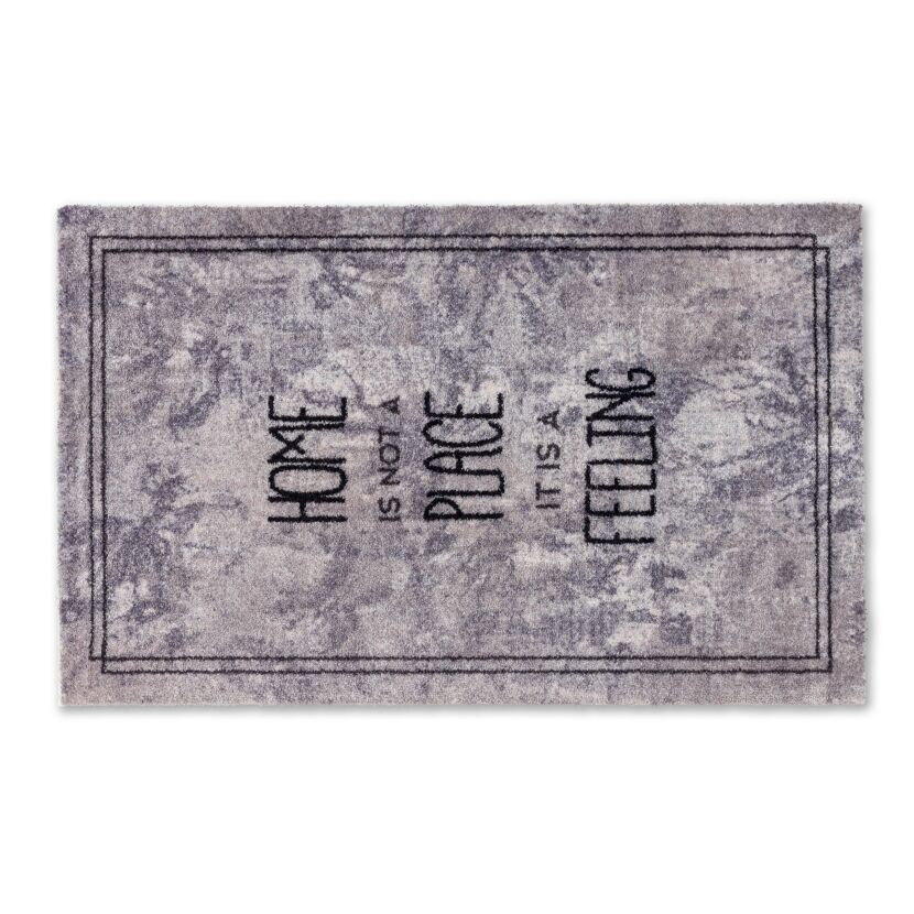 Grauer Fußabtreter mit der Aufschrift "Home is not a place it is a feeling"