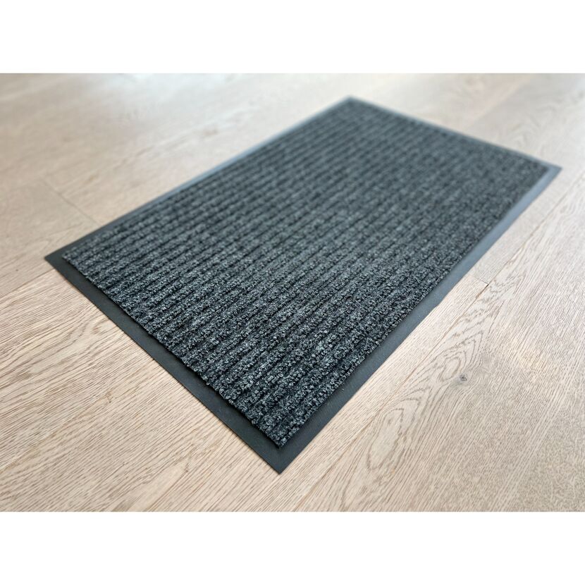 Anthrazitfarbene Fußmatte auf hellem Holzboden.