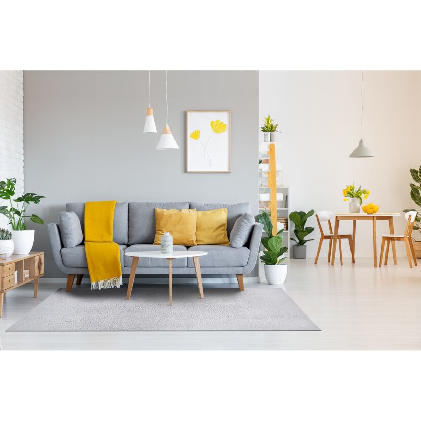 Wohnzimmer mit grauem Sofa, gelber Decke und hellem Teppich