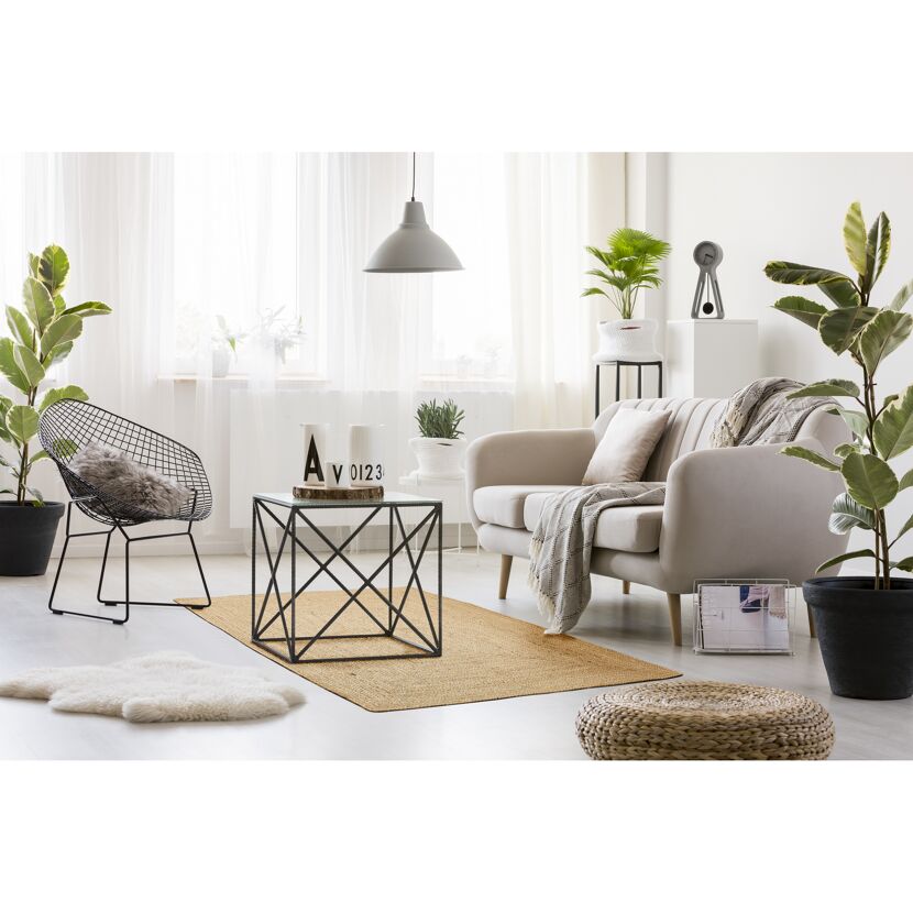 Heller, moderner Wohnbereich mit Juteteppich, beiger Couch und schwarzen Metallmöbeln.