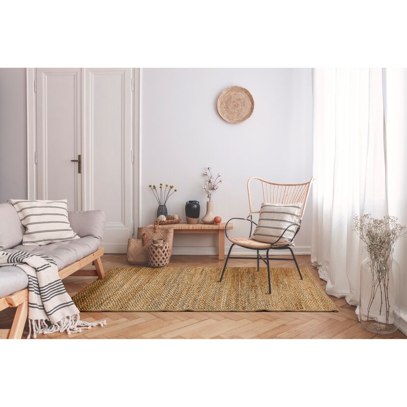 Wohnzimmer mit Juteteppich, Sofa und Korbsessel