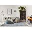 Wohnzimmer mit hellgrünem Sofa, Hocker, Vitrine und gemustertem Teppich