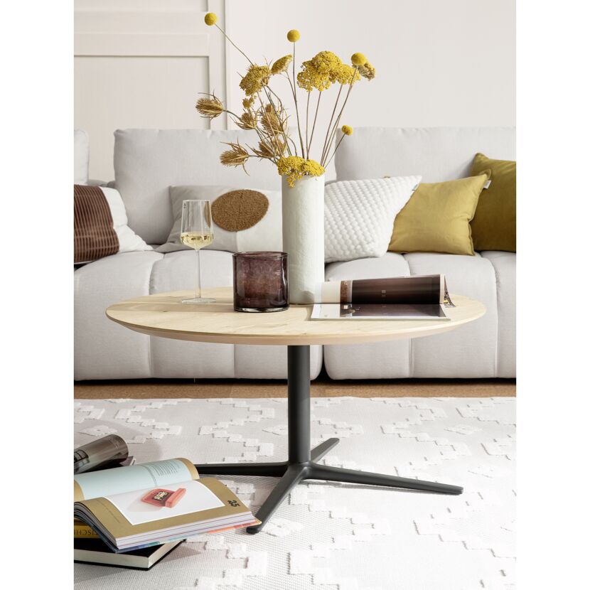 Runder Holztisch mit Deko vor Sofa