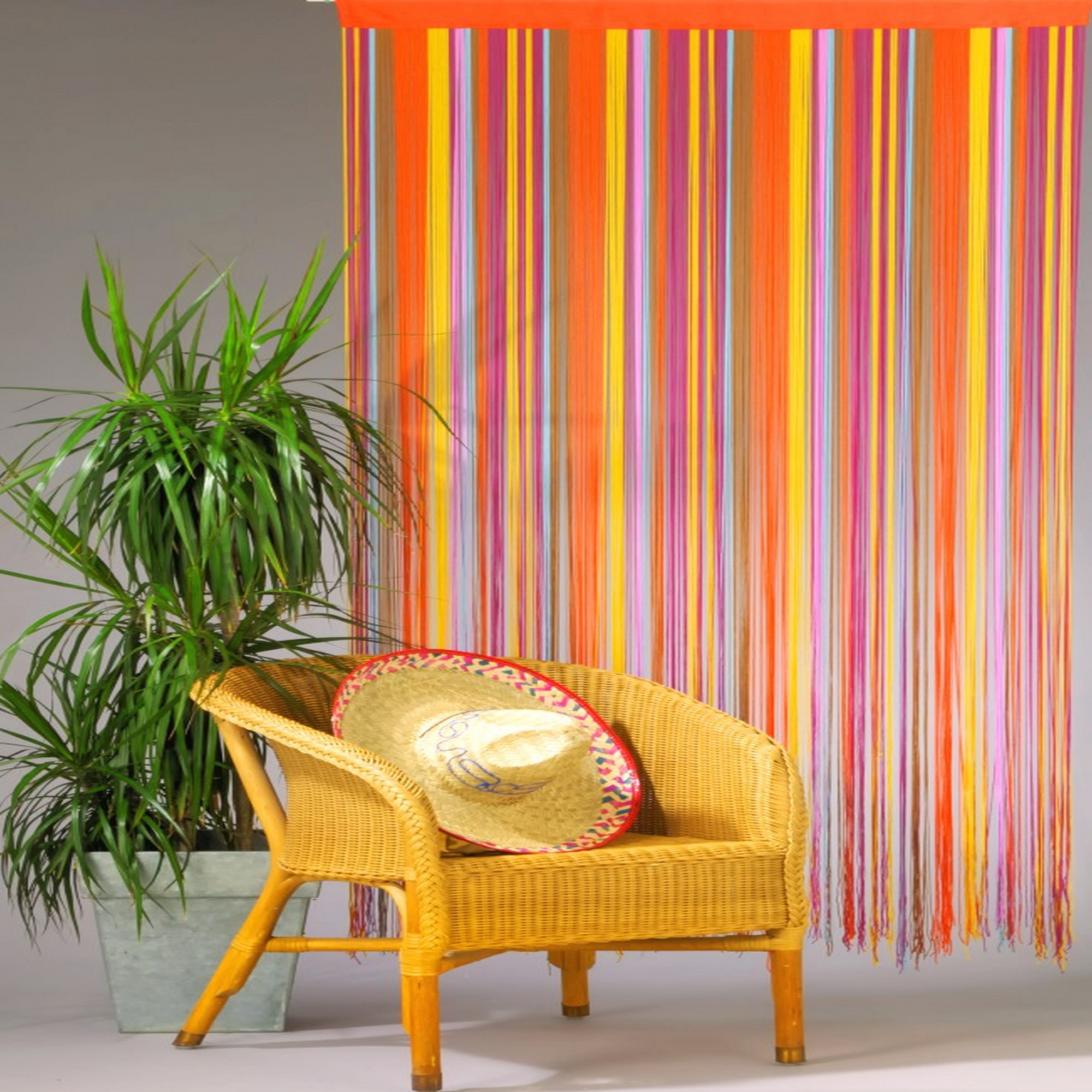 Bunter Dekovorhang, Korbstuhl, Pflanze und Sombrero