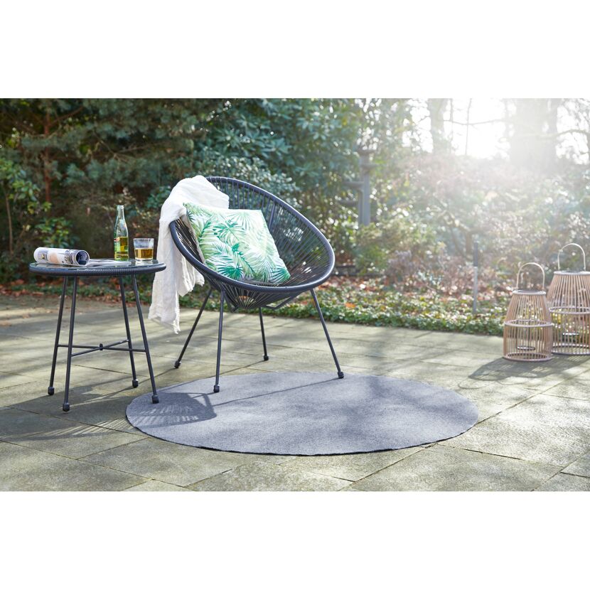 Schwarzer Gartenstuhl mit Kissen auf grauem, rundem Teppich.