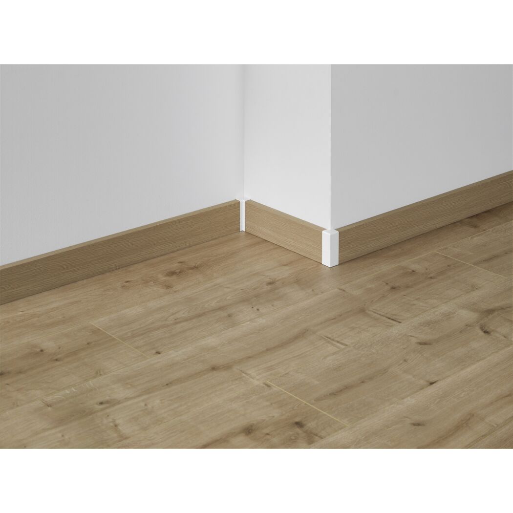 Ecke einer Holzfußleiste an einer weißen Wand