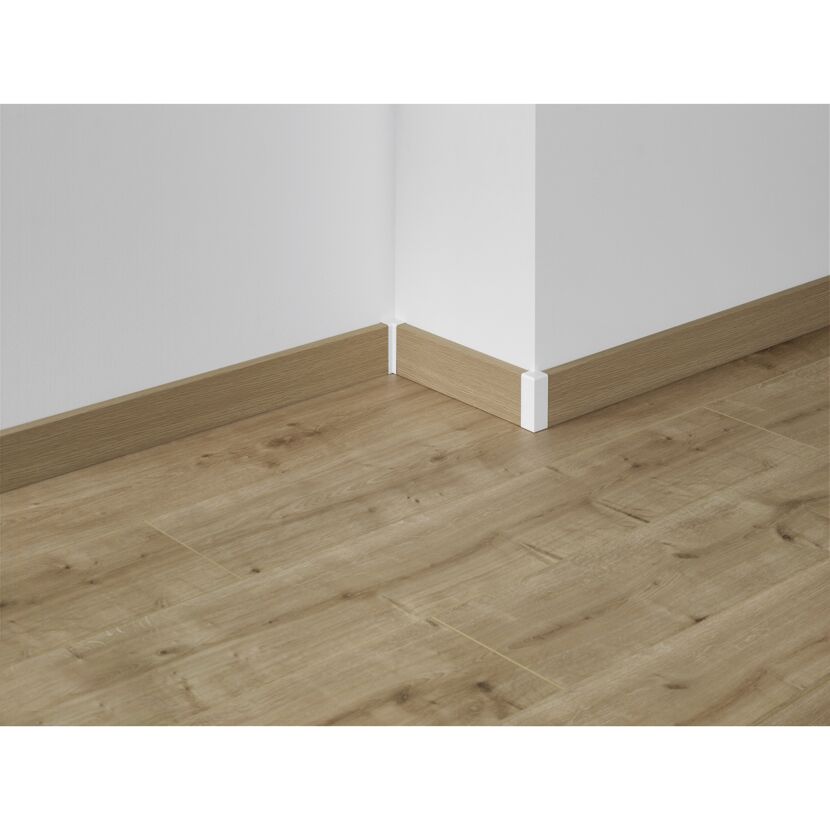 Ecke einer Holzfußleiste an einer weißen Wand