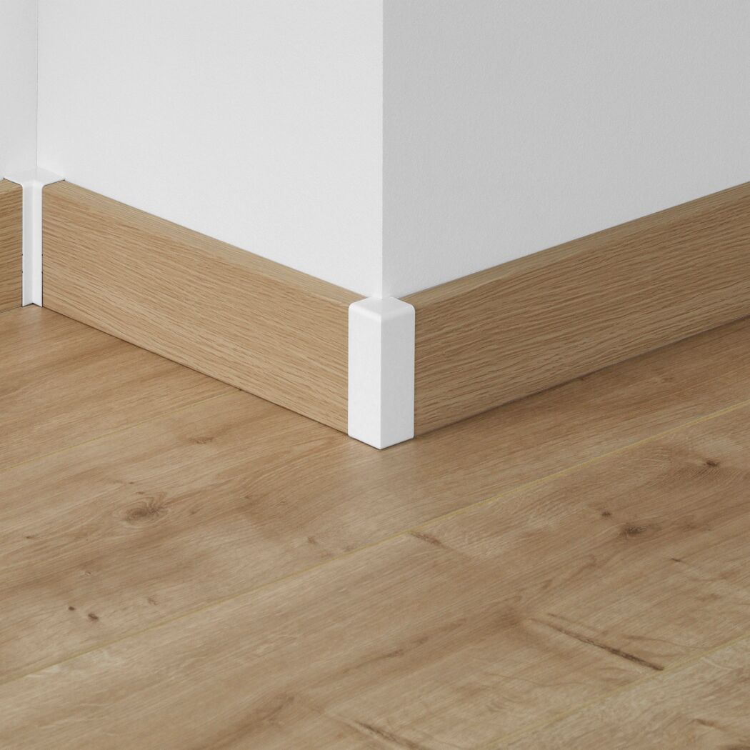 Ecke einer weißen Wand mit brauner Holzfußleiste