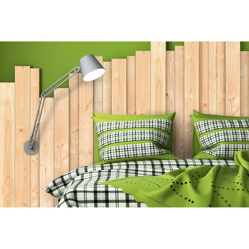 Bett mit grün-karierter Bettwäsche und einer Leselampe an der Holzwand