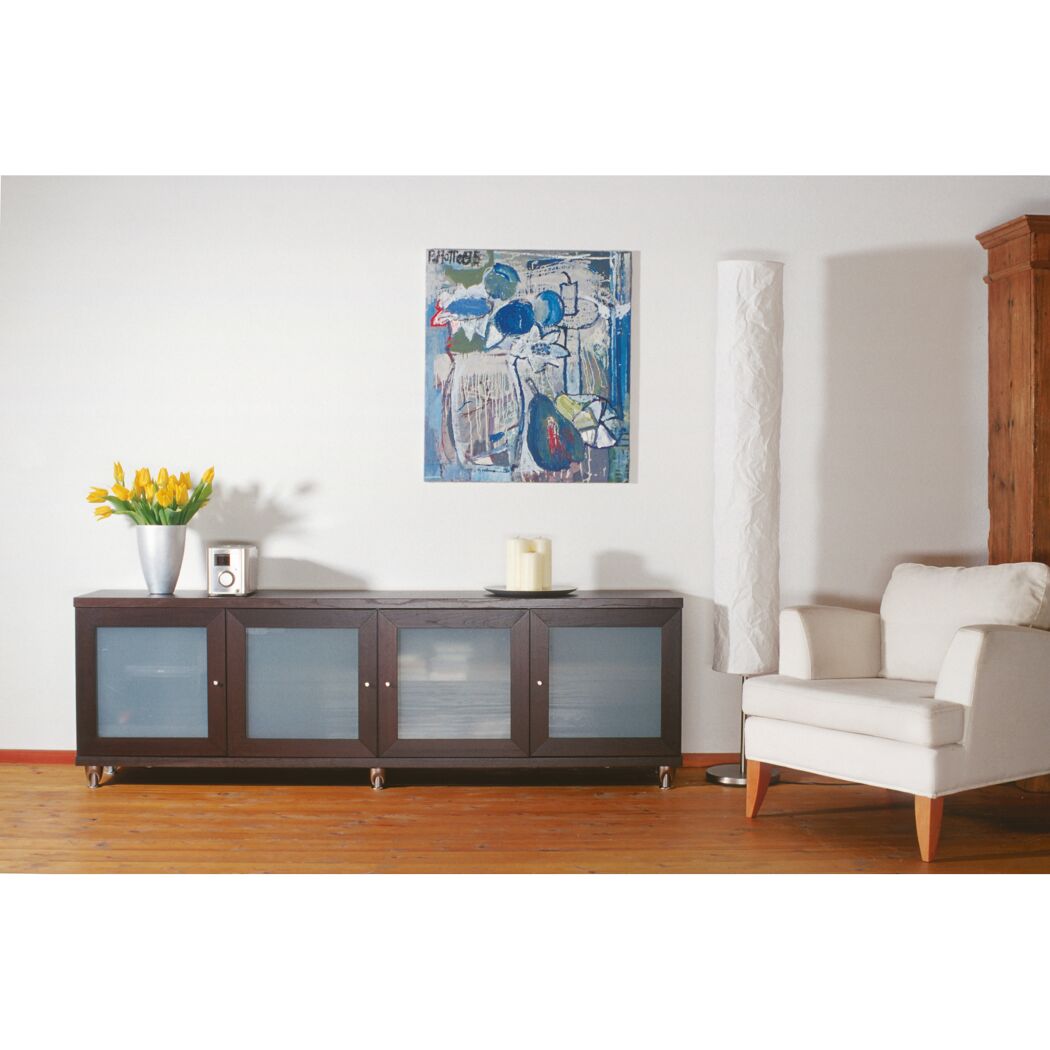 Einrichtungsidee mit dunklem Sideboard, gelben Tulpen und weißem Sessel.