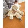 Kind sitzt mit großem Teddy auf Korkparkett