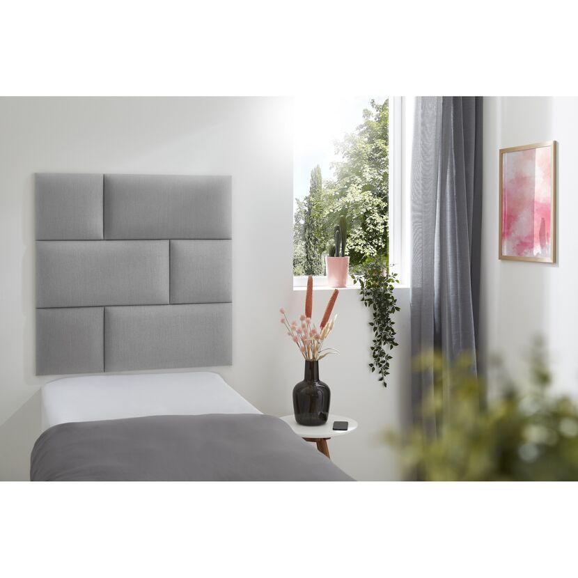 Graues Wandkissen Inari an einem Bett