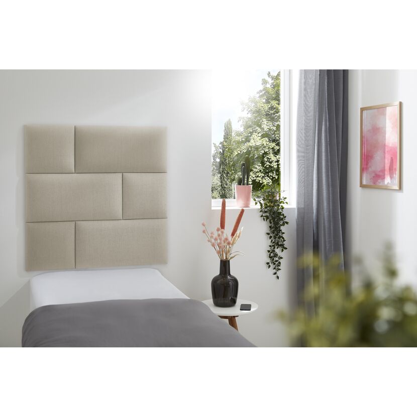 Beige gepolstertes Wandkissen Inari über einem Bett.