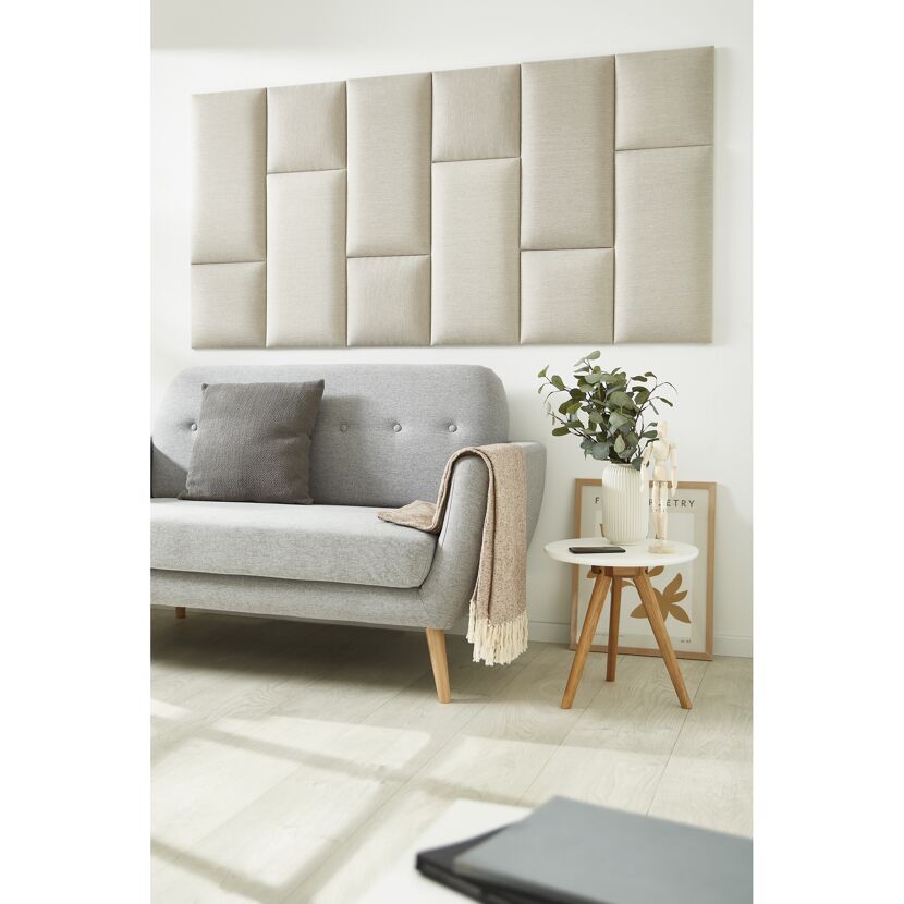 Beiges Wandkissen Inari an der Wand über einem Sofa.