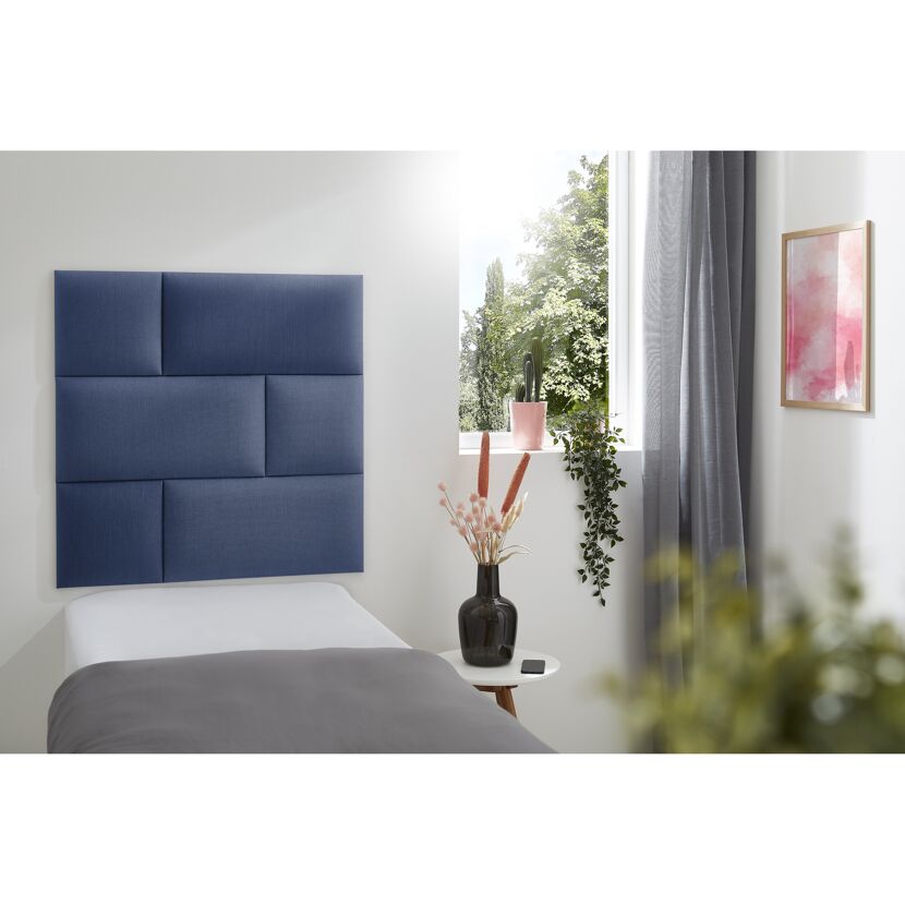Blaues Wandkissen Inari an einem Bett.