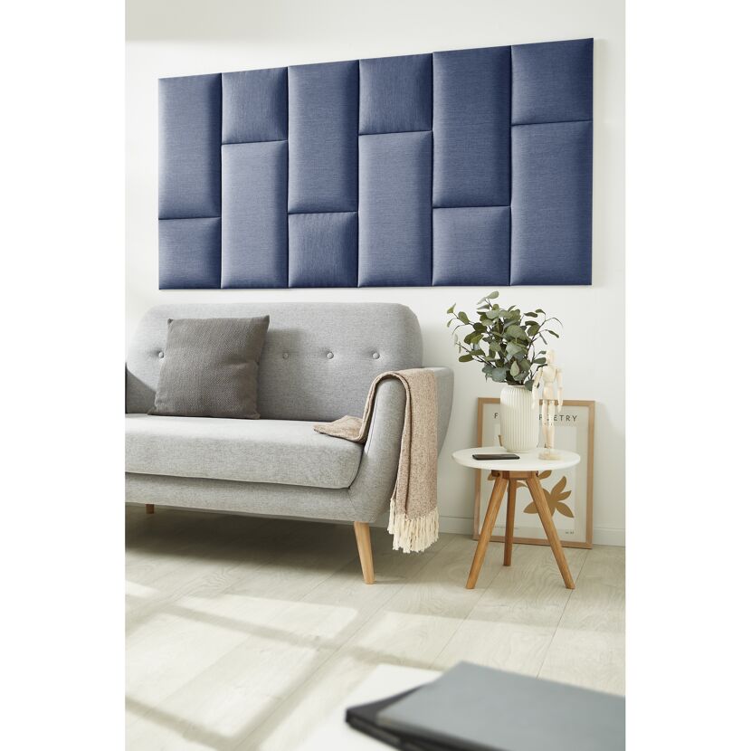 Blaues Wandkissen Inari an der Wand über einem Sofa