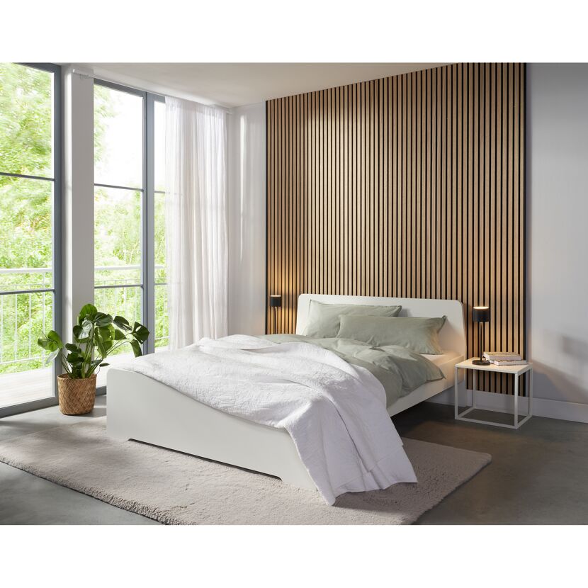 Weißes Bett mit Bettzeug und Holzwand