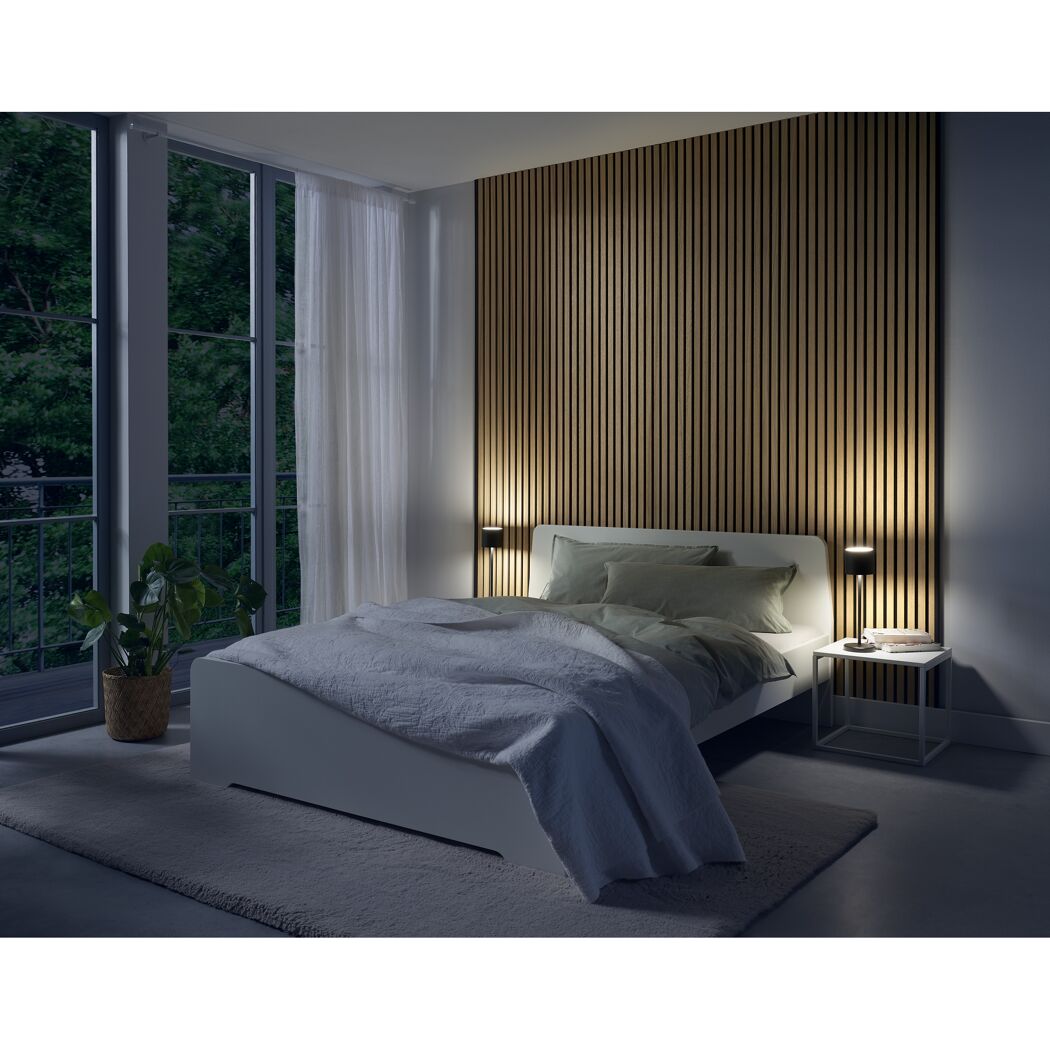 Schlafzimmer mit Bett, Nachttisch und zwei Lampen.