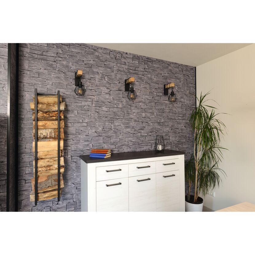 Holzstapel und Kommode vor Steinwand