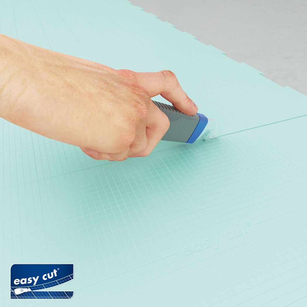 Hand schneidet Trittschalldämmung mit Cuttermesser zu.