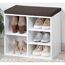 Weißer Schuhschrank mit braunem Sitzkissen und Schuhen.