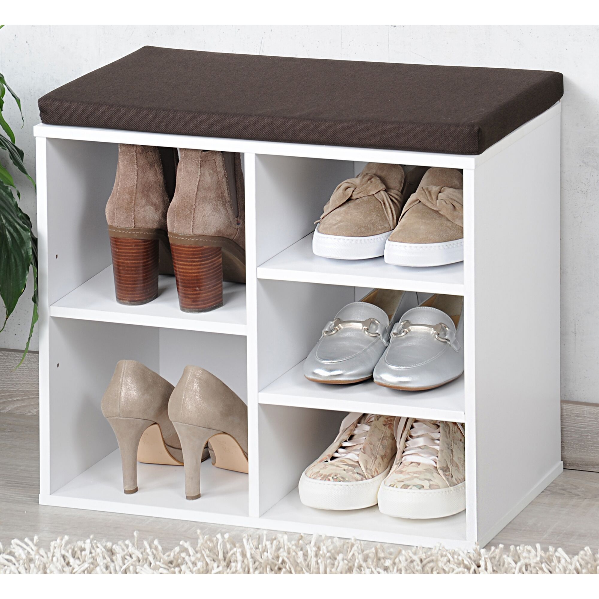 Weißer Schuhschrank mit braunem Sitzkissen und Schuhen.